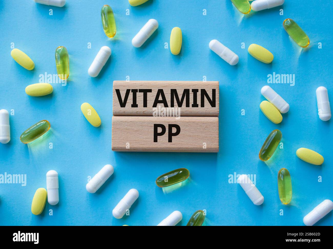 Symbole de vitamine PP. Mot concept Vitamin PP sur des blocs de bois. Beau fond rose avec des pilules. Concept de médecine et de vitamine PP. Copier l'espace Banque D'Images