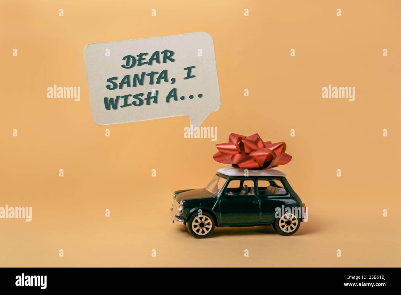 Voiture jouet avec un arc rouge sur le dessus et un message qui dit cher Père Noël, je souhaite un Banque D'Images
