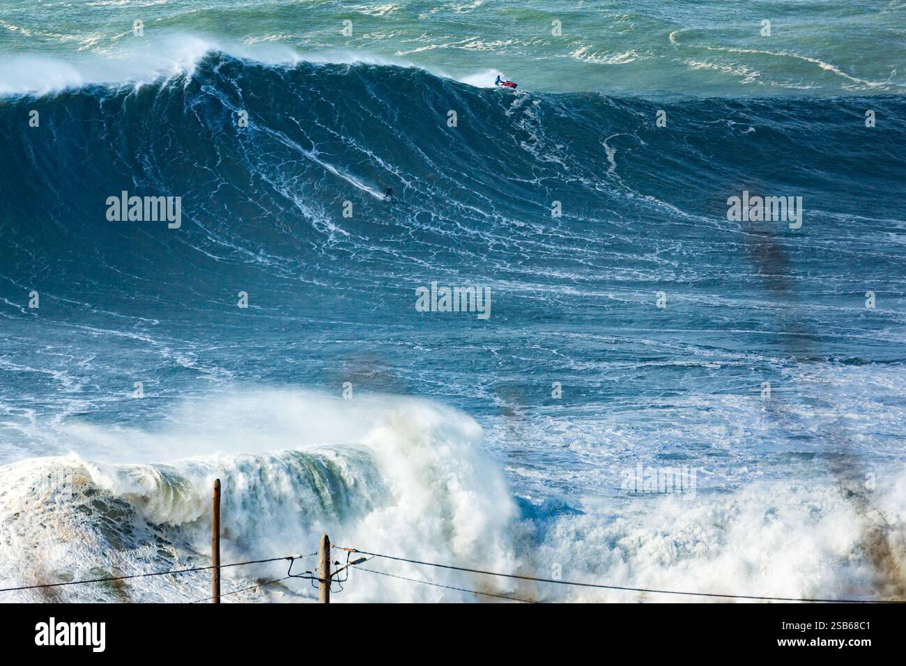 Un surfeur de grosses vagues roule sur une vague lors d’une séance de surf à Praia do Norte à Nazaré le 28 février 2025. Du 27 au 30 de 2025, de nombreux surfeurs tentent de surfer sur ces vagues massives, dans le but de battre de nouveaux records du monde. Banque D'Images