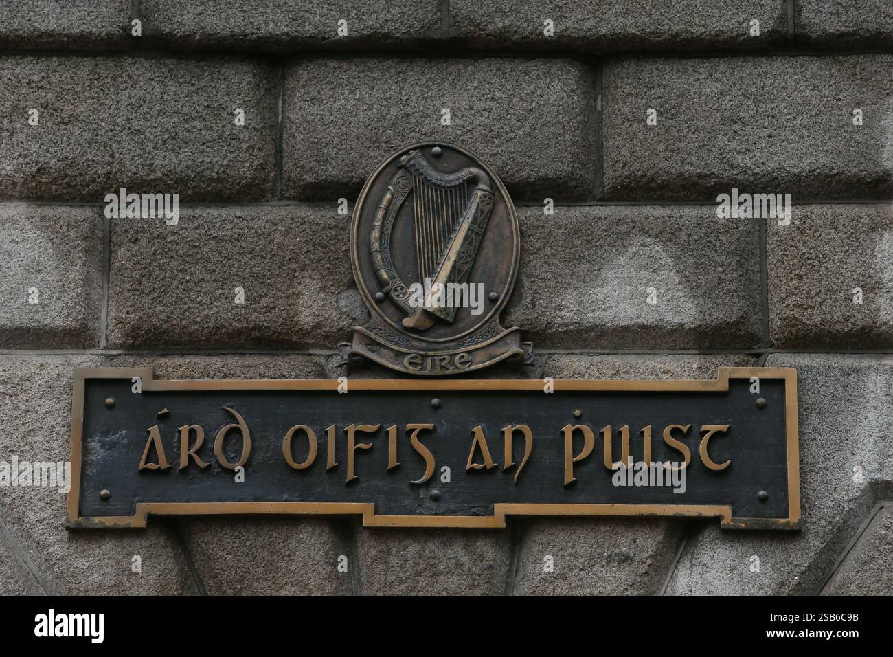 Dublin, Irlande - 28 janvier 2025 - un vieux panneau irlandais avec le titre du General Post Office (Post Office HQ) en langue irlandaise et une plaque en relief avec une grande harpe sur le mur d'entrée latéral du GPO sur O'Connell Street Banque D'Images