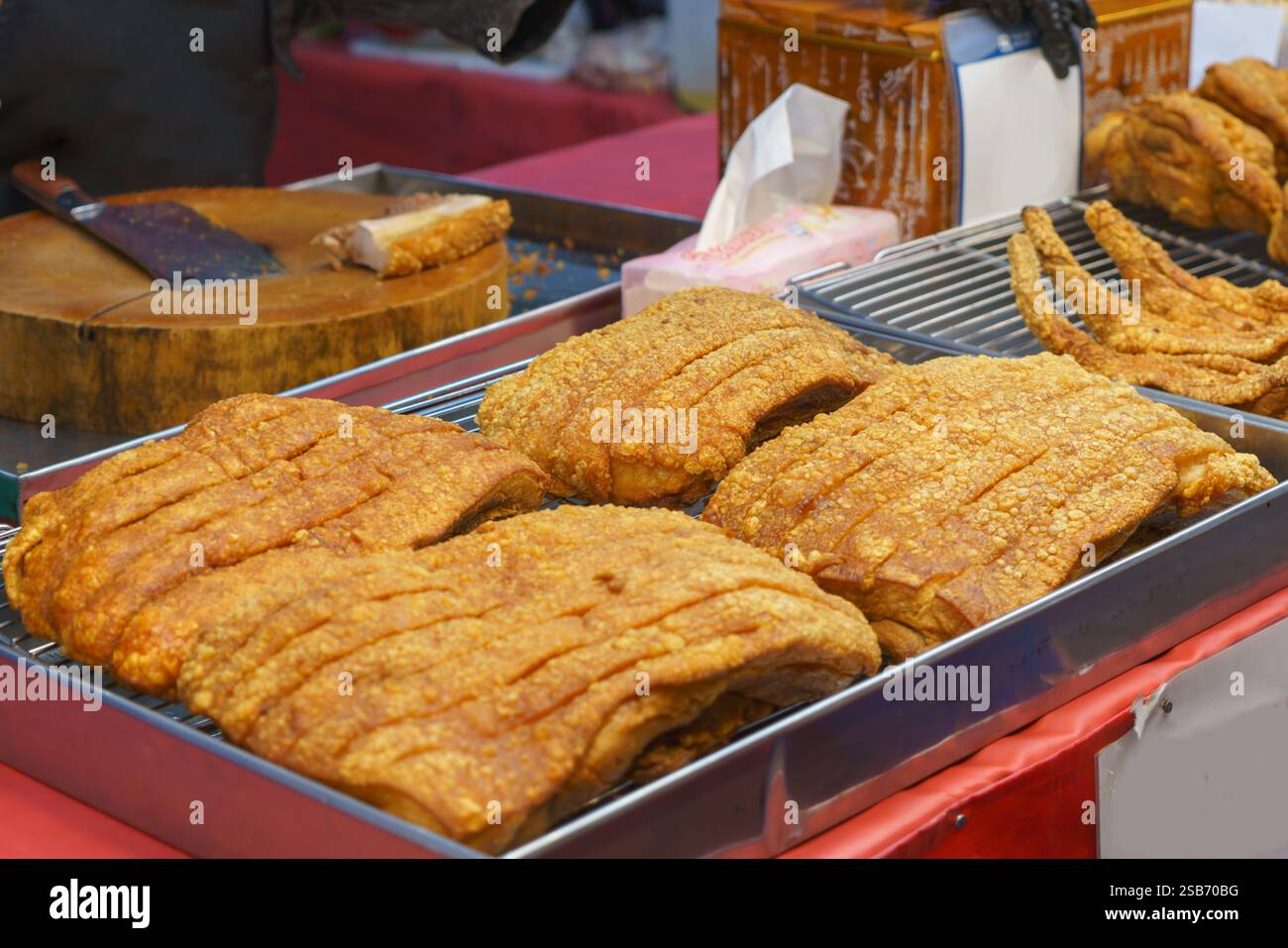 Vue rapprochée de tranches de poitrine de porc croustillantes parfaitement cuites, présentant leur croûte dorée et leur viande tendre. Le plat salé est affiché sur un tra Banque D'Images