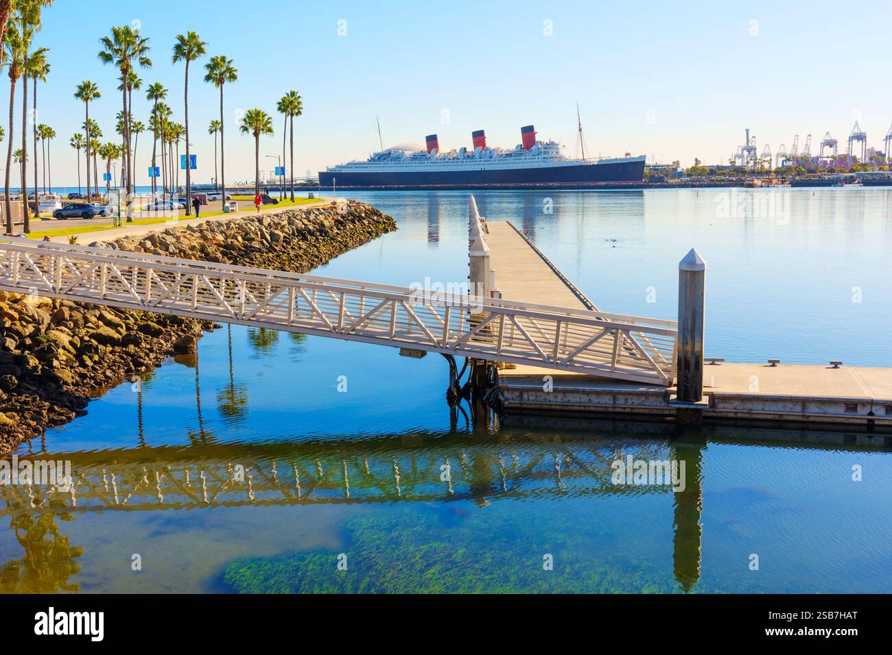 Long Beach, Californie - 15 janvier 2025 : vue d'un quai reflétant dans les eaux sereines de long Beach avec le navire Queen Mary en arrière-plan et Banque D'Images