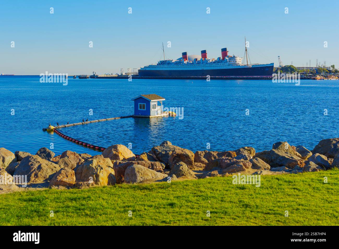 Long Beach, Californie - 15 janvier 2025 : vue du navire Queen Mary à long Beach depuis une zone herbeuse, avec une petite structure flottante sur le w Banque D'Images