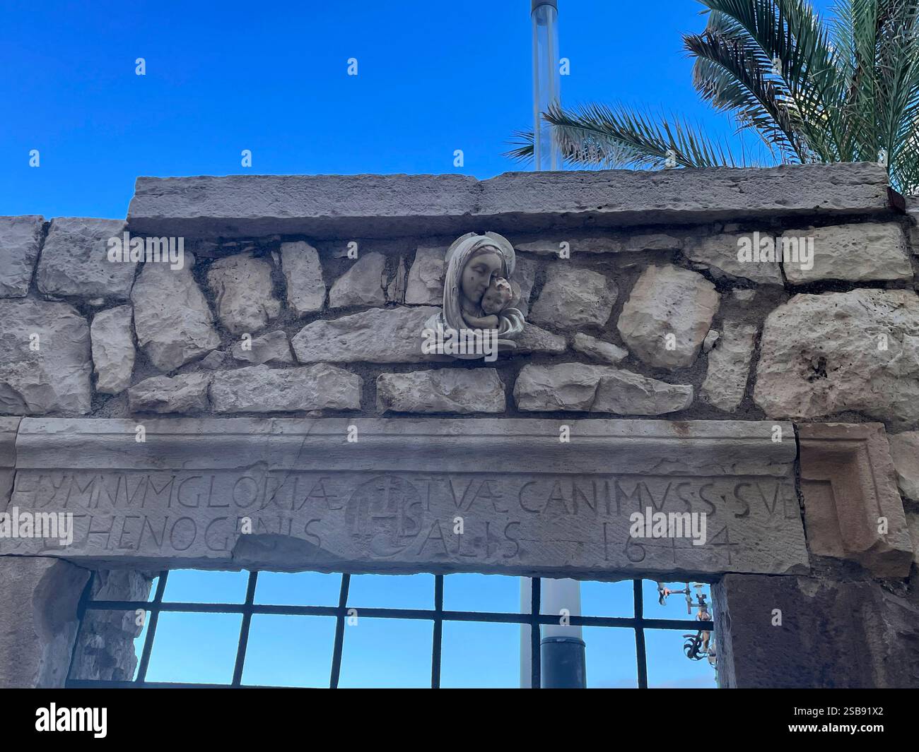 Détails architecturaux anciens à Molfetta, Italie. Des éléments chrétiens sur une porte de pierre et une inscription en latin disant : «nous chantons un hymne à votre gloire». - Image de stock capturée avec un smartphone