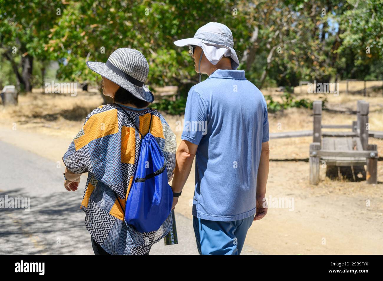 Couple allant sur leur promenade quotidienne dans une banlieue verdoyante par une journée d'été ensoleillée. Herbe séchée le long du chemin. Californie. Banque D'Images