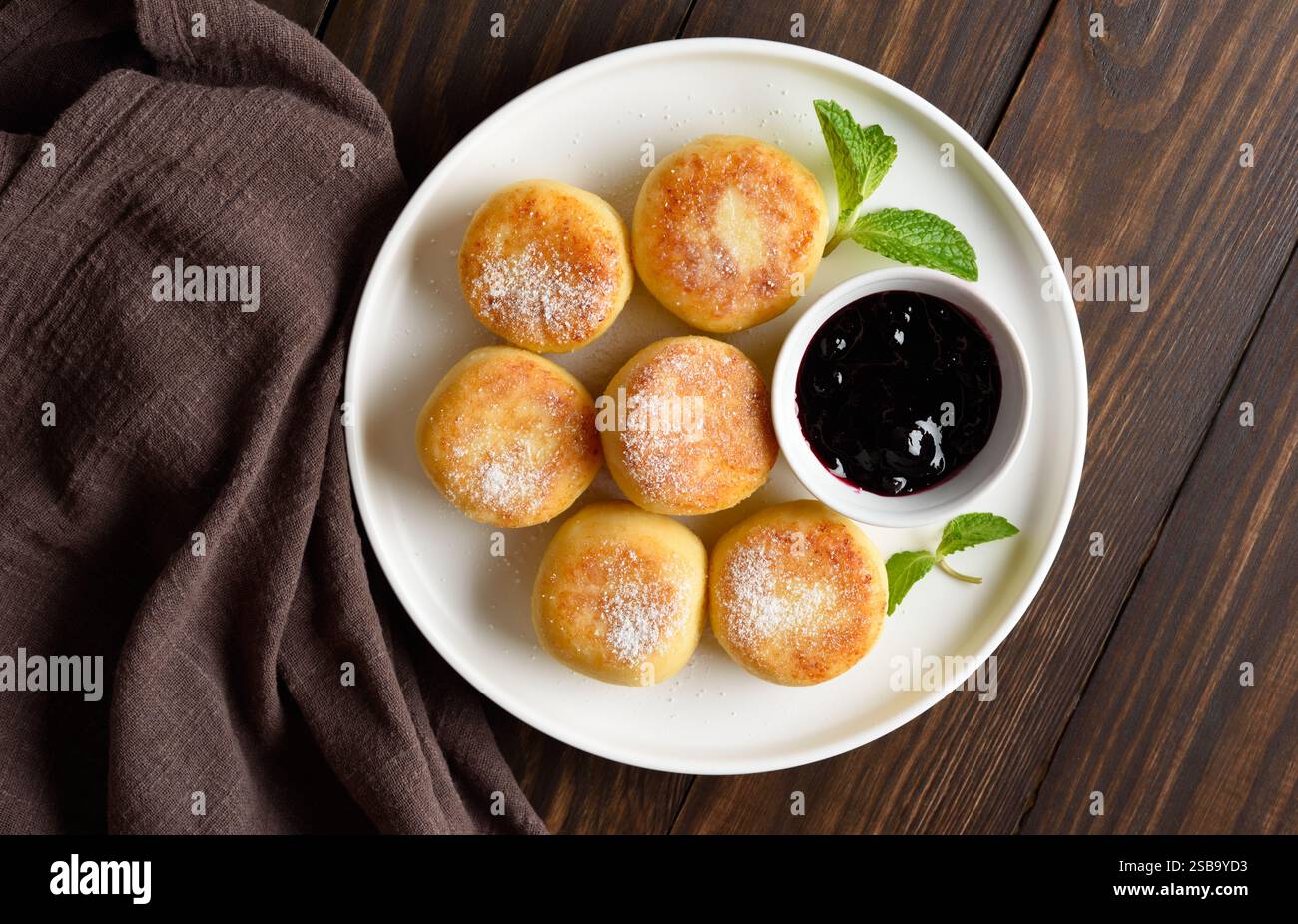 Cheesecakes au fromage cottage (beignets syrniki ou caillé) servis avec de la confiture de myrtilles sur fond de bois. Concept d'alimentation saine. Vue de dessus, plat l Banque D'Images