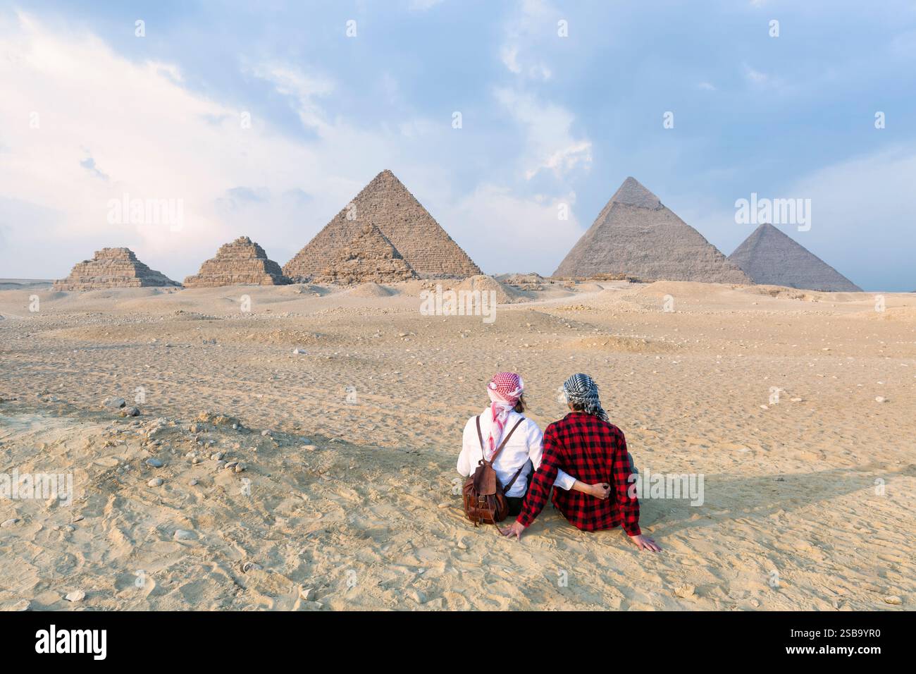 Vue arrière couple amant, touristes femme et homme avec fond de chapeau la pyramide de Gizeh égyptienne, coucher du soleil le Caire, Egypte. Banque D'Images