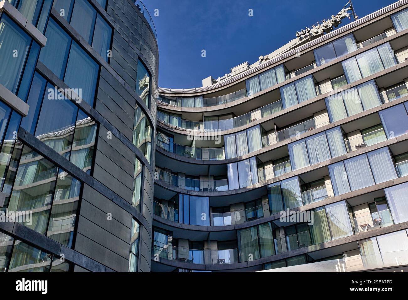 Deux bâtiments modernes de plusieurs étages avec façades courbes et nombreuses fenêtres et balcons. Un bâtiment est majoritairement gris, l'autre présente du verre Banque D'Images