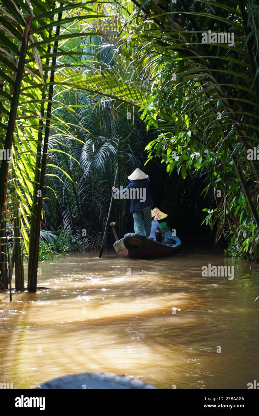 Femme vietnamienne portant un chapeau conique traditionnel debout sur un bateau sur le Mékong, Vietnam Banque D'Images