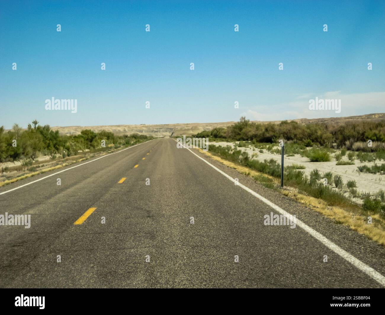 Une longue route vide sans voitures ni personnes. Le ciel est clair et bleu. La route est une autoroute à deux voies sans circulation Banque D'Images