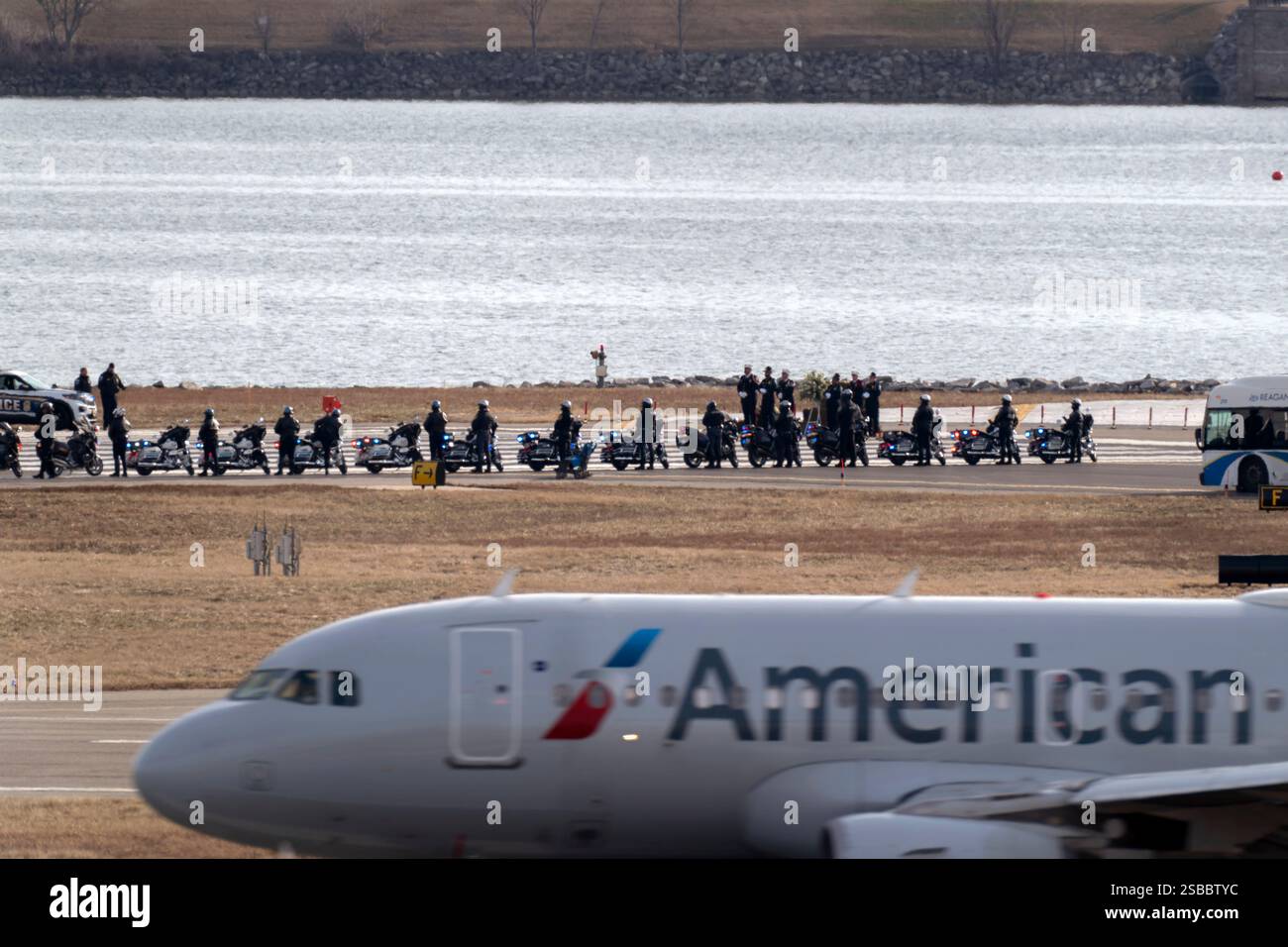 An American Airlines jet passes as police officers escort buses ...