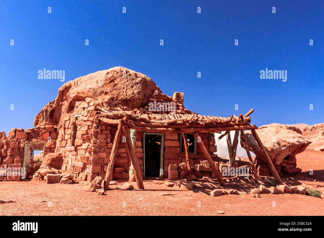 Une petite maison avec un porche se trouve dans un désert. La maison est en pierre et a un toit de chaume. Le paysage désertique est aride et sec, sans veget Banque D'Images