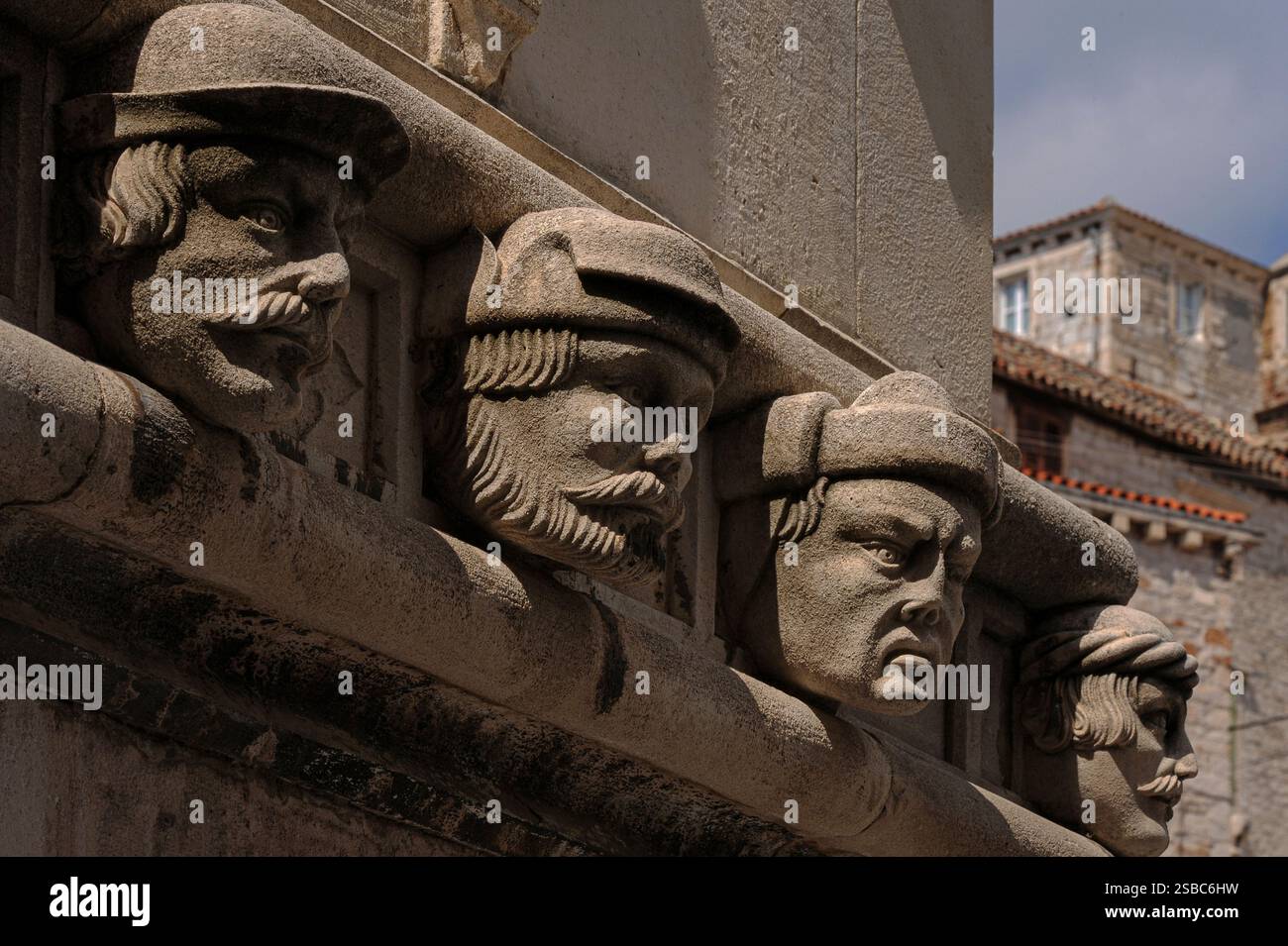 Quatre visages du XVe siècle : des hommes de la Renaissance, trois avec des moustaches, représentés dans une frise sculpturale courant autour des trois absides de la cathédrale Saint-Jacques à Šibenik, Dalmatie, Croatie. Il présente 71 têtes grandeur nature sculptées par le sculpteur vénitien et architecte du XVe siècle Giorgio da Sebenico ou Georgius Mathei Dalmaticus - peut-être toutes les personnes qu'il connaissait. Banque D'Images