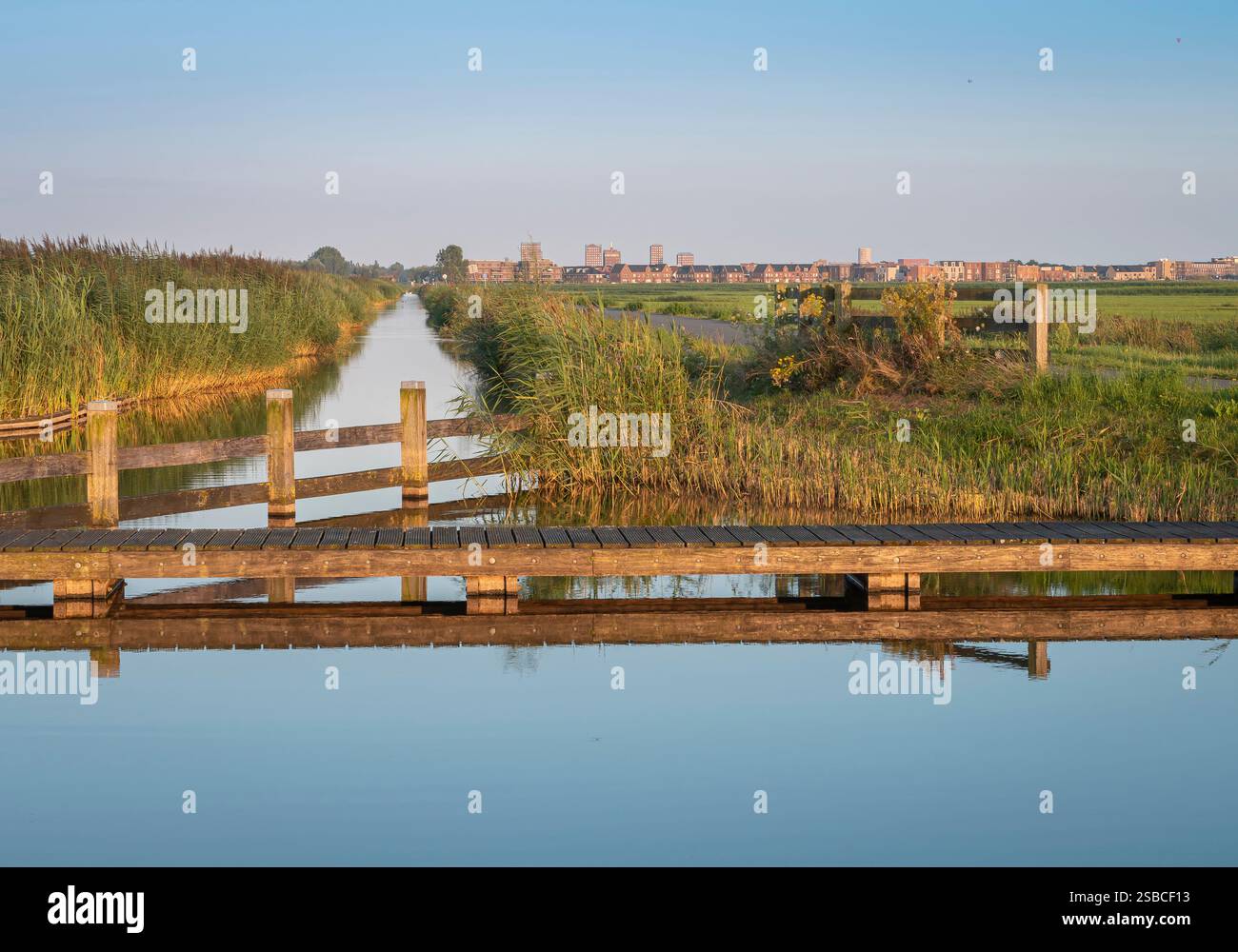 Canal d'eau avec jetée reflétée dans l'eau et la ville d'Amersfoort au loin. Paysage hollandais. Banque D'Images