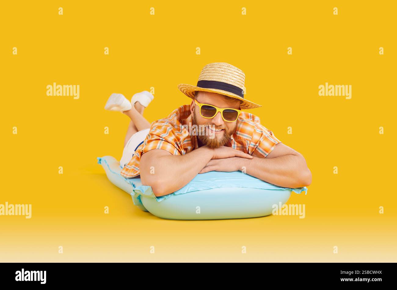 Homme heureux se relaxant sur un matelas gonflable sur fond orange Banque D'Images