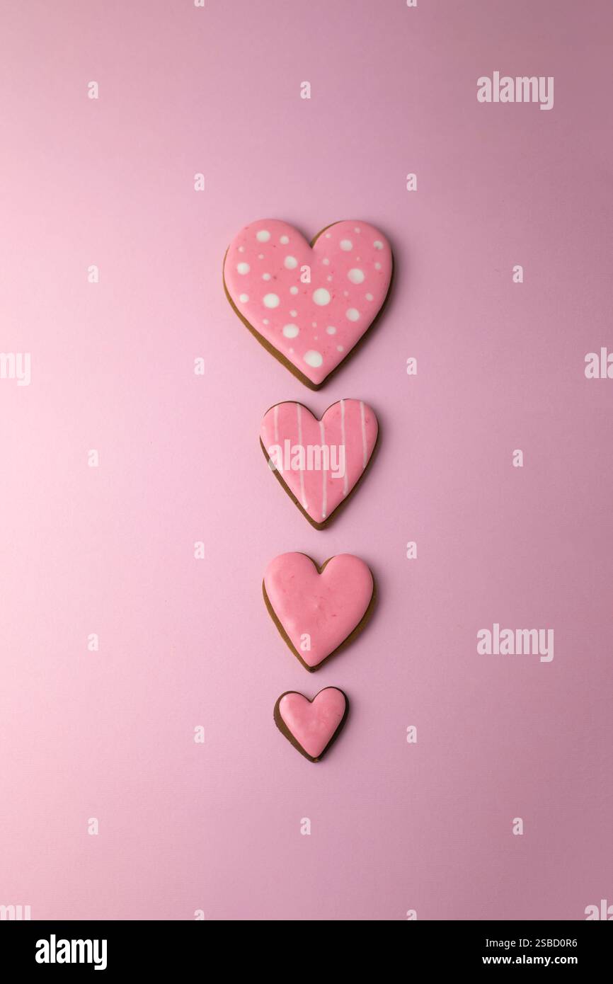 Biscuits en pain d'épices en forme de coeurs avec glaçage rose, concept de cuisson créative minimaliste pour la Saint-Valentin Banque D'Images