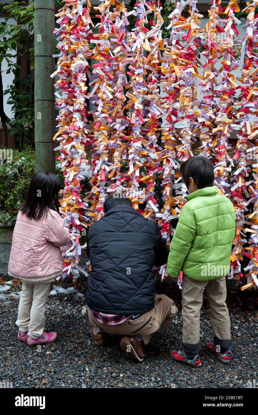 Les gens attachent leur 'omikuji' (oracle papier bonne ou mauvaise chance) à une ficelle pendant 'hatsumode' (visite du sanctuaire du nouvel an) à Taga Taisha, Hikone, Japon. Banque D'Images