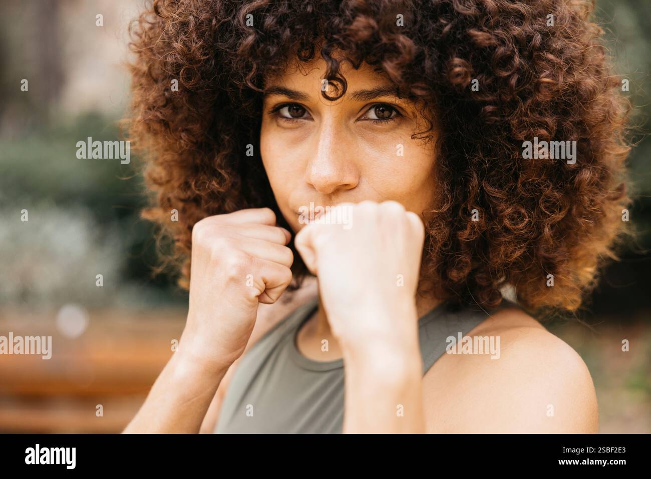 Une femme déterminée pratiquant la posture de combat à l'extérieur, montrant la force et la confiance dans un environnement de parc. Banque D'Images
