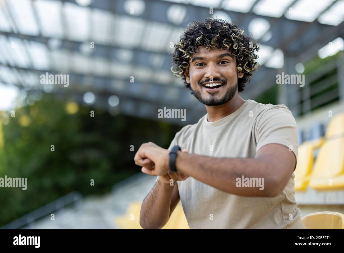L'homme utilise un bracelet de fitness de montre intelligente pendant l'entraînement. Athlète est satisfait des résultats de son entraînement, sourit et regarde la caméra. Banque D'Images
