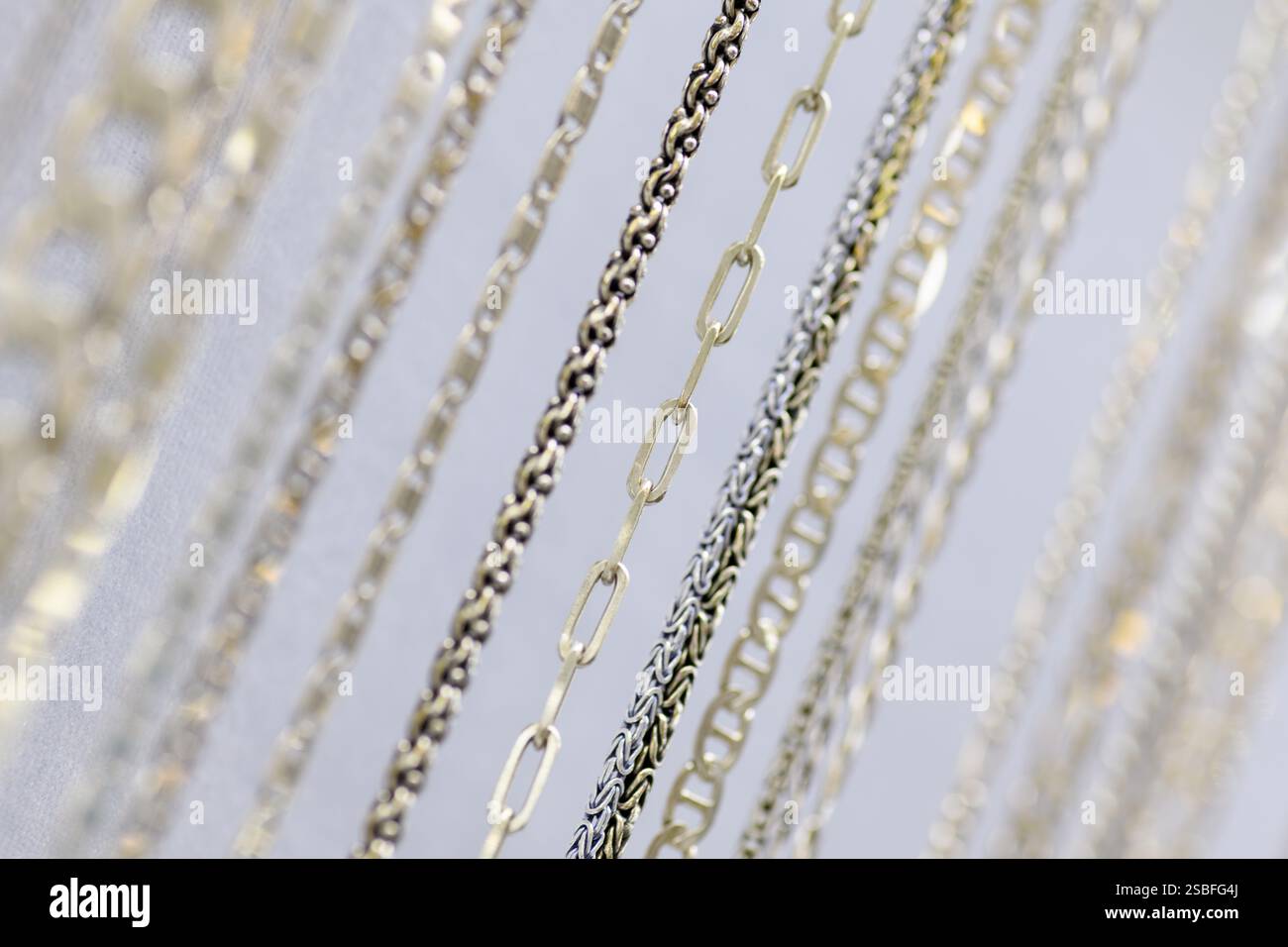 Une grande collection de colliers chaîne en argent élégamment affichés sur un stand de bijoux blanc Banque D'Images
