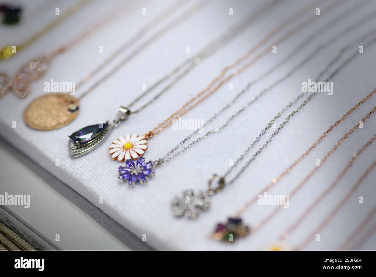 Gros plan de divers colliers en argent avec différents motifs de pendentifs, magnifiquement affichés sur un présentoir à bijoux Banque D'Images