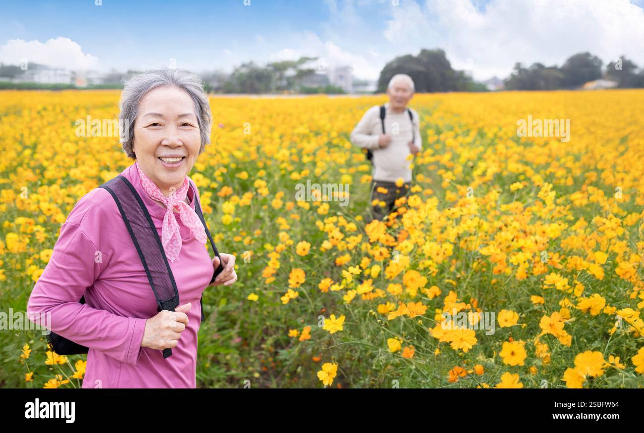 Heureux couple aîné randonnée sur le sentier par des plantes de fleurs Banque D'Images
