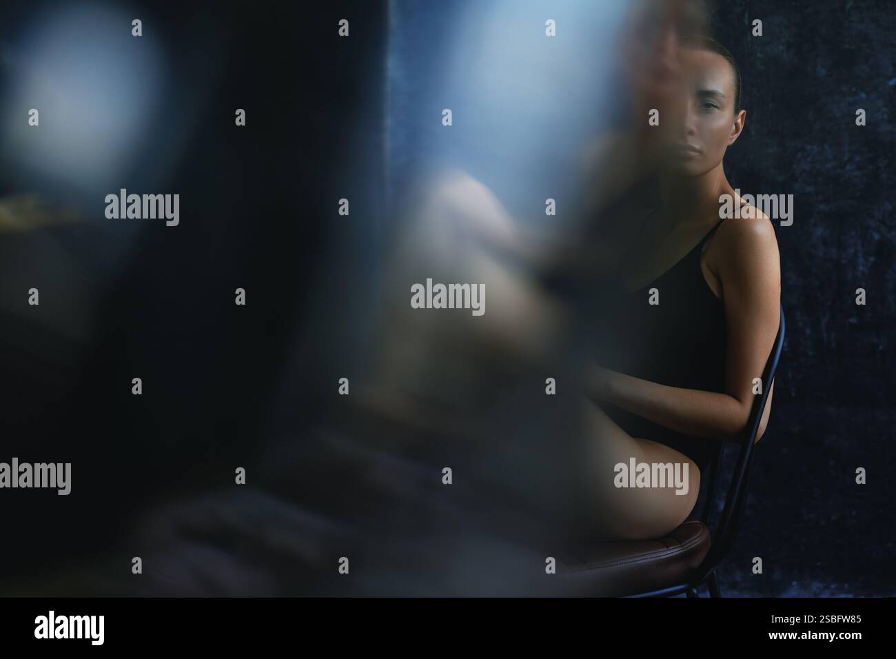 Femme blonde assise sur une chaise. Réflexions et distorsions de la lumière Banque D'Images