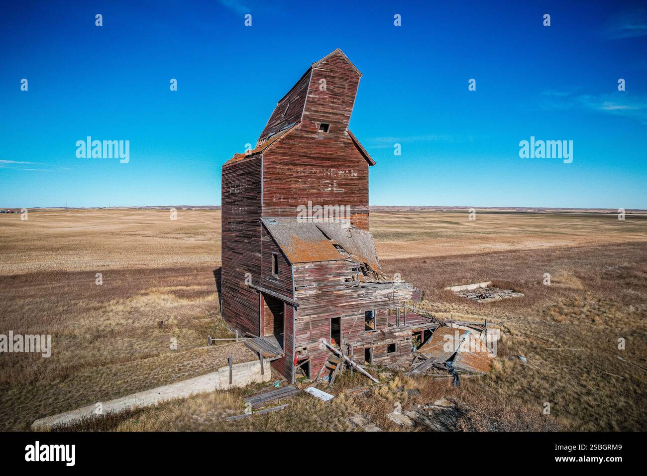 Un grand bâtiment en briques avec un toit incliné. Le bâtiment est dans un champ. Le ciel est bleu Banque D'Images