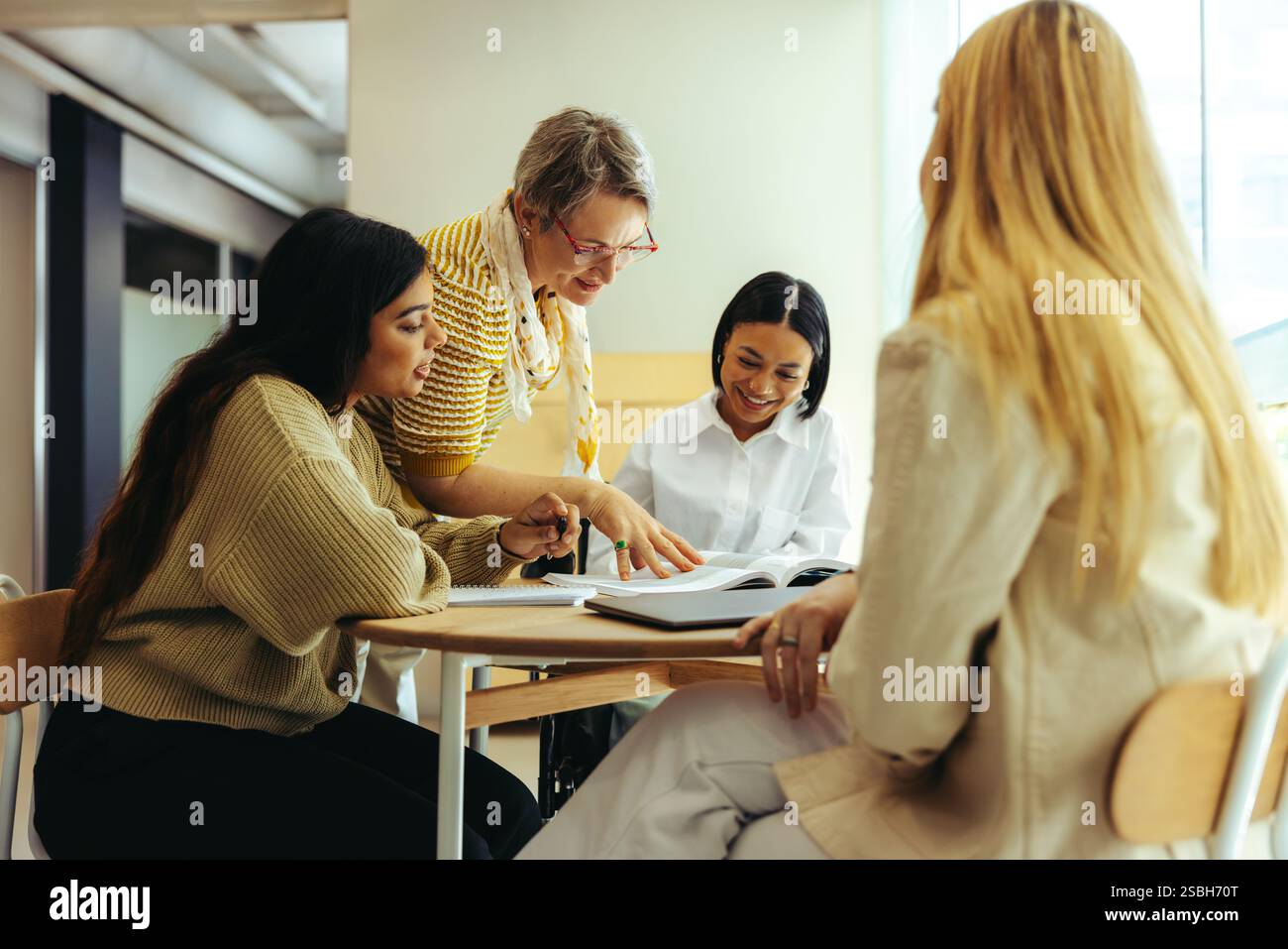 Un enseignant dévoué s'engage avec divers étudiants dans un environnement éducatif, discutant des cours et favorisant l'apprentissage dans un brillant, collaborati Banque D'Images