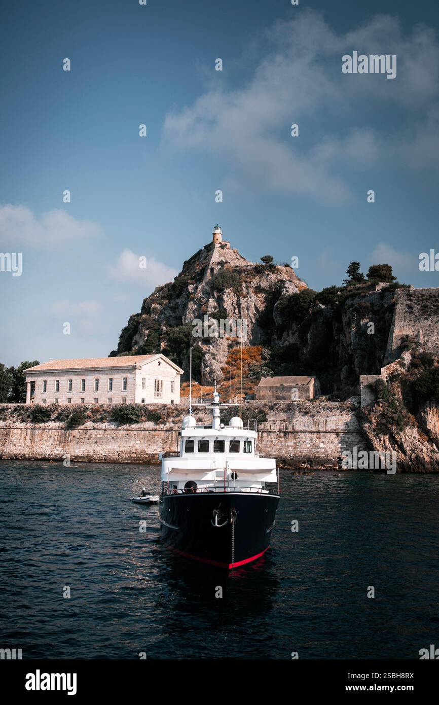 L'image montre une scène côtière pittoresque avec un grand bateau amarré pour un phare Banque D'Images