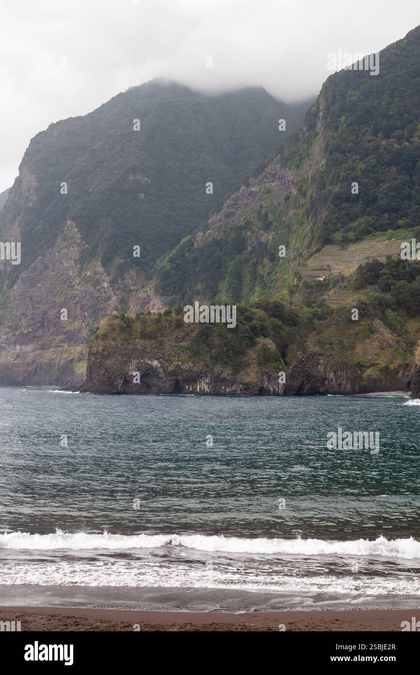 Plage de sable de l'océan Atlantique, avec de petites vagues côtières. Montagnes - falaises en arrière-plan, couvertes de verdure intense. Top dans le cloud. Seix Banque D'Images
