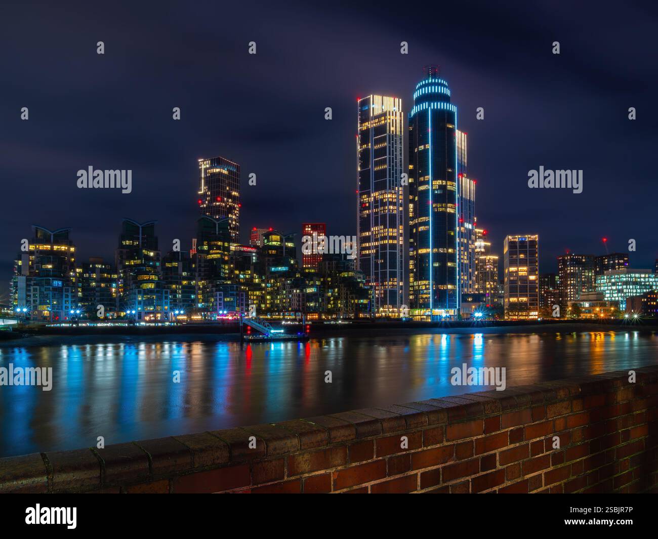 Londres, Royaume-Uni - 27 octobre 2024 : un paysage urbain animé de Londres la nuit avec des gratte-ciel illuminés reflétant sur une rivière calme de la Tamise. Banque D'Images