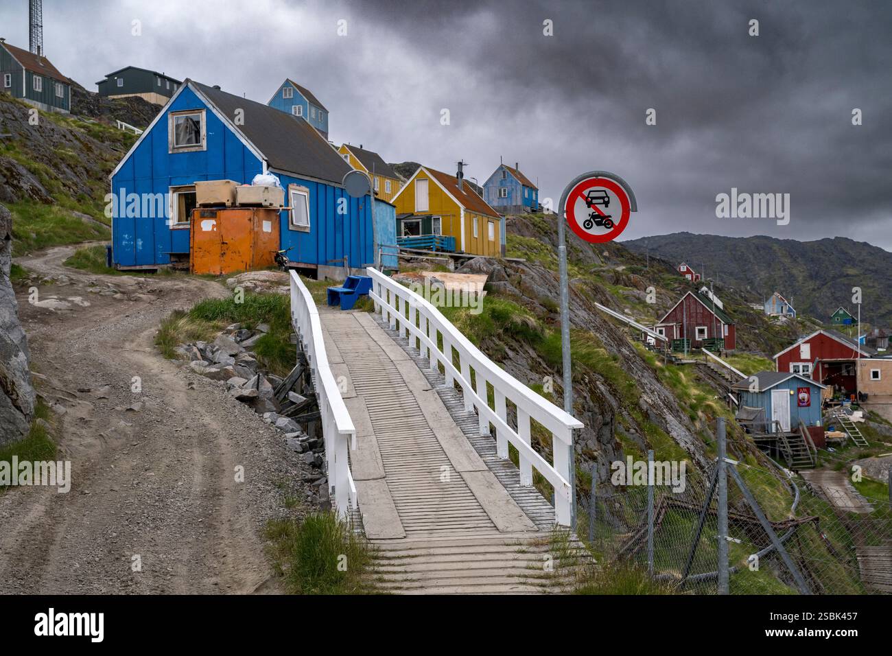 Le village de Sarfannguit, au Groenland, présente des maisons vibrantes contre un ciel sombre, mettant en valeur sa beauté sinistre et son charme historique. Banque D'Images