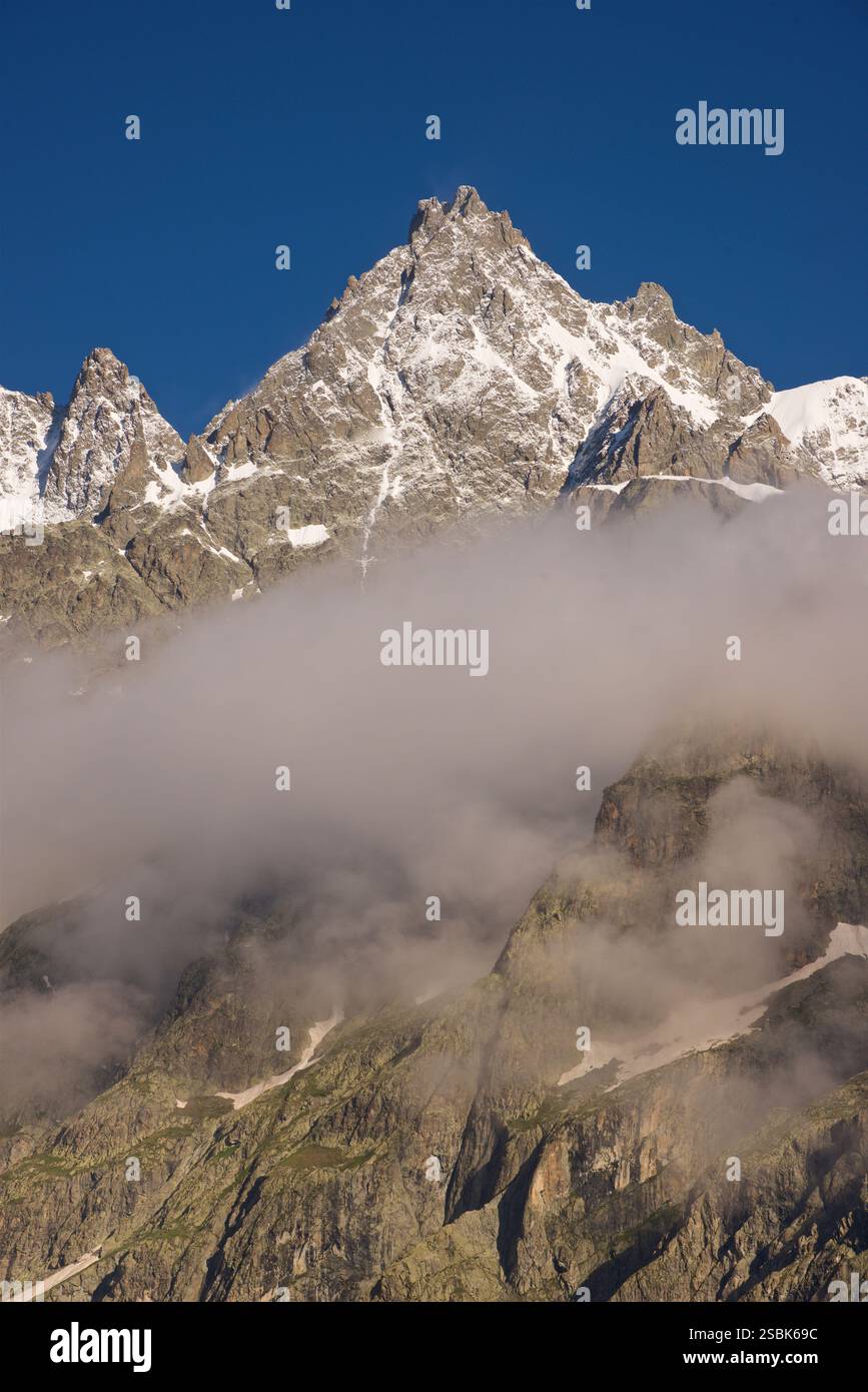 Le sommet de la montagne sur la photo est 'le Pelvoux' dans le massif des Écrins, France. Le Pelvoux est un sommet important situé dans les Alpes du Dauphiné, près du village d'Ailefroide en France. Il a plusieurs sommets, dont le plus haut est la pointe Puiseux, qui culmine à 3 946 mètres (12 946 pieds). L'aspect déchiqueté et accidenté du pic et du paysage environnant, combiné avec la vue depuis le pré de Madame Carle, sont révélateurs du Pelvoux. C'est l'un des sommets les plus reconnus de la région des Écrins. Banque D'Images
