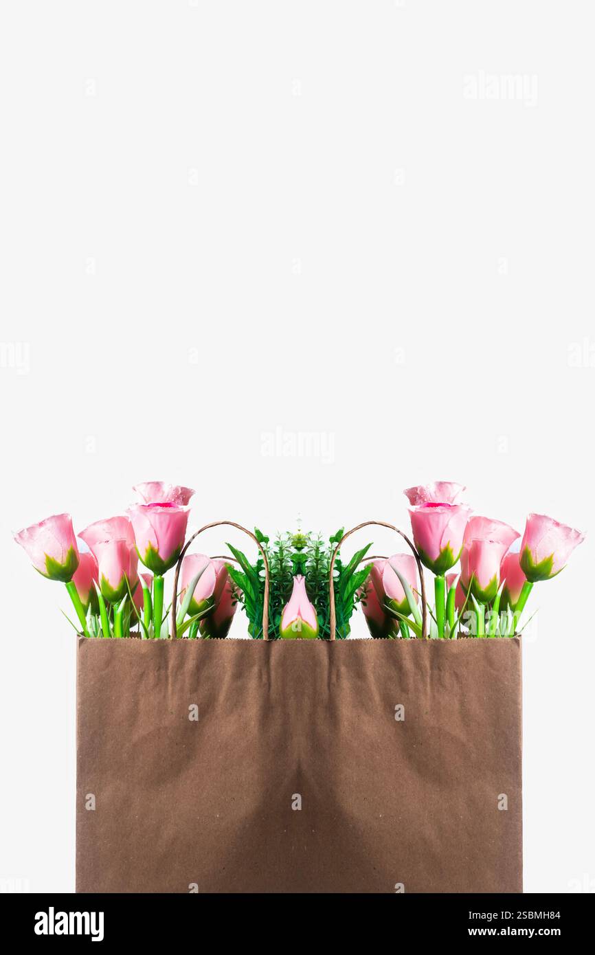 Fleurs roses à l'intérieur d'un sac en papier brun sur un fond blanc propre et un emballage écologique. Banque D'Images