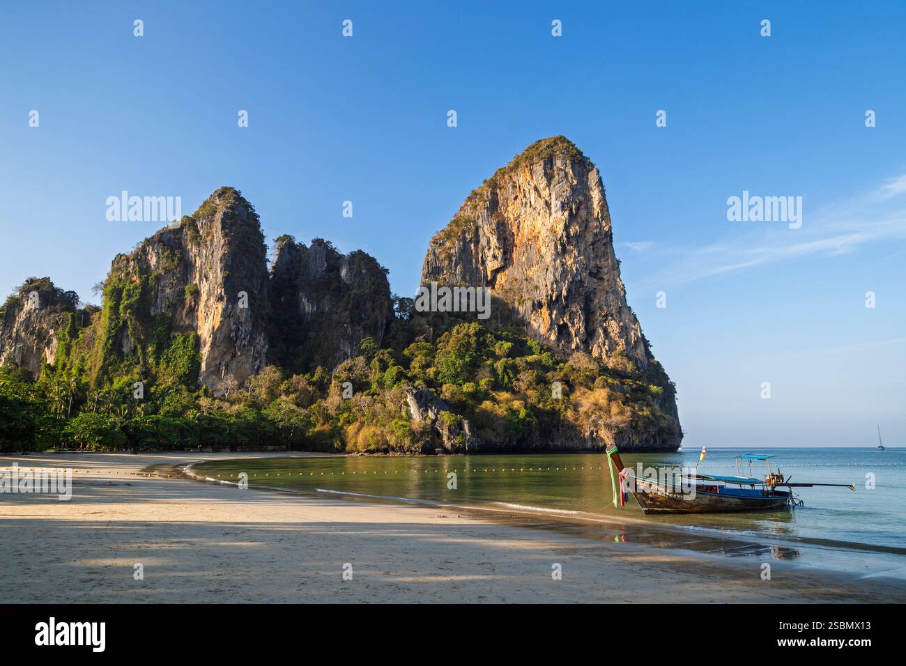 Vue panoramique sur la plage vide et idyllique de Railay West et les hautes falaises de calcaire à Railay, Krabi, Thaïlande, par un matin ensoleillé. Banque D'Images