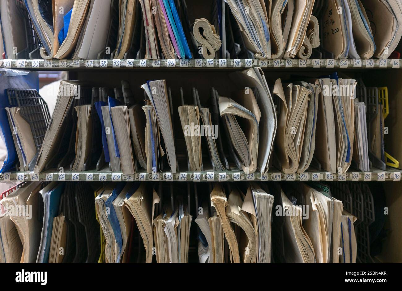 Divers cahiers, papiers et formulaires sur une étagère sous numéros de série, détail du bureau de poste. Banque D'Images