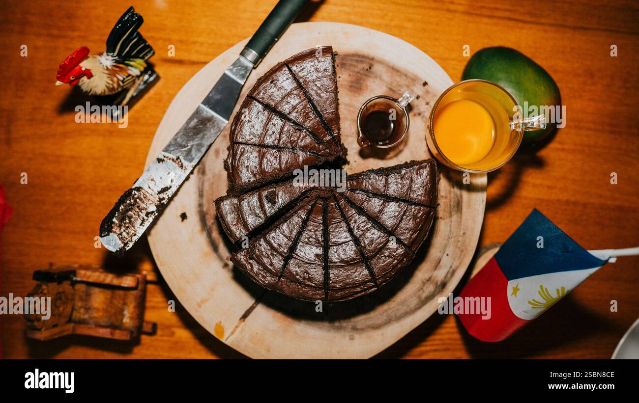 Une tranche de gâteau est coupée en morceaux et placée sur une planche à découper en bois. Un couteau est à côté du gâteau. Une tasse de café est également sur la table Banque D'Images