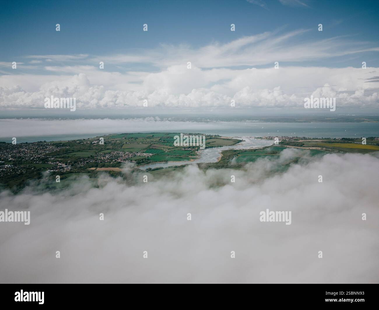 Un ciel nuageux avec une rivière en arrière-plan. Le ciel est principalement nuageux avec quelques taches de bleu Banque D'Images