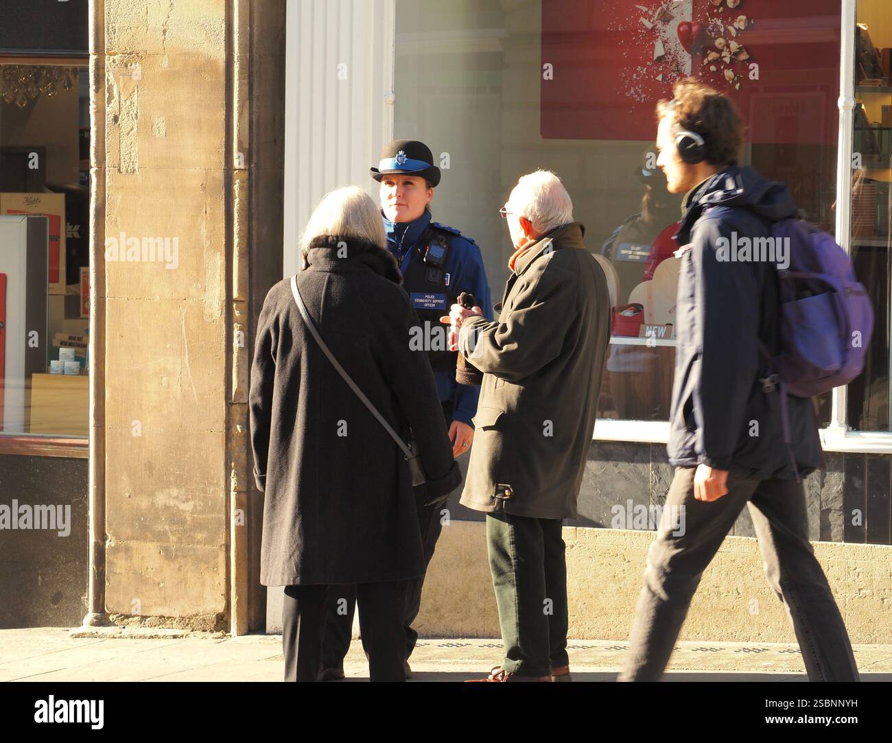 Agent de soutien communautaire de la police (PCSO) en uniforme chargé de répondre aux demandes de renseignements de deux membres plus âgés du public dans le centre-ville de Bath, Bath Somerset. Banque D'Images