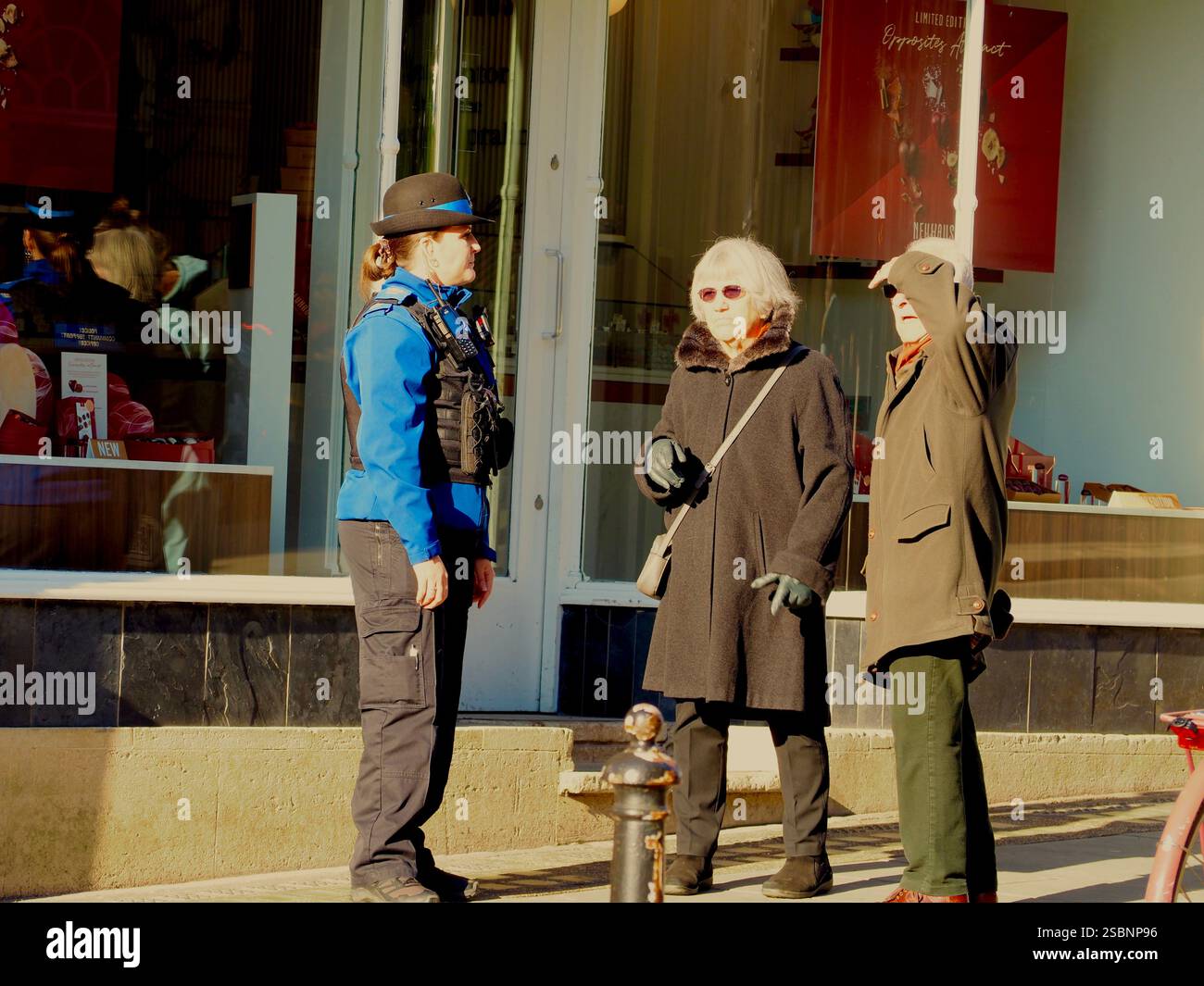 Agent de soutien communautaire de la police (PCSO) en uniforme chargé de répondre aux demandes de renseignements de deux membres plus âgés du public dans le centre-ville de Bath, Bath Somerset. Banque D'Images
