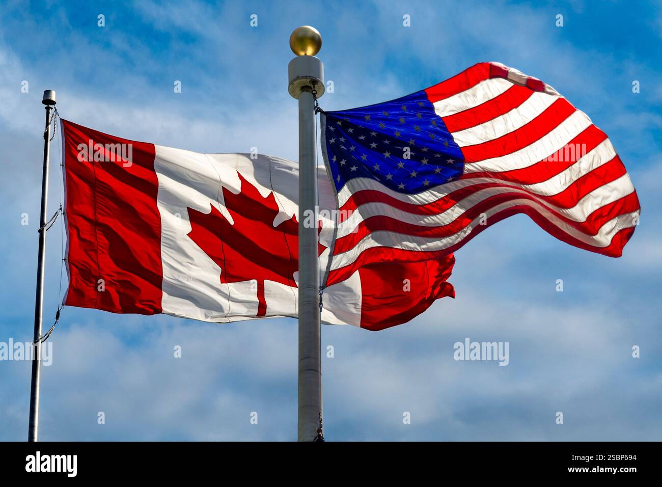 Drapeaux du Canada et des États-Unis volant dans un vent fort Banque D'Images