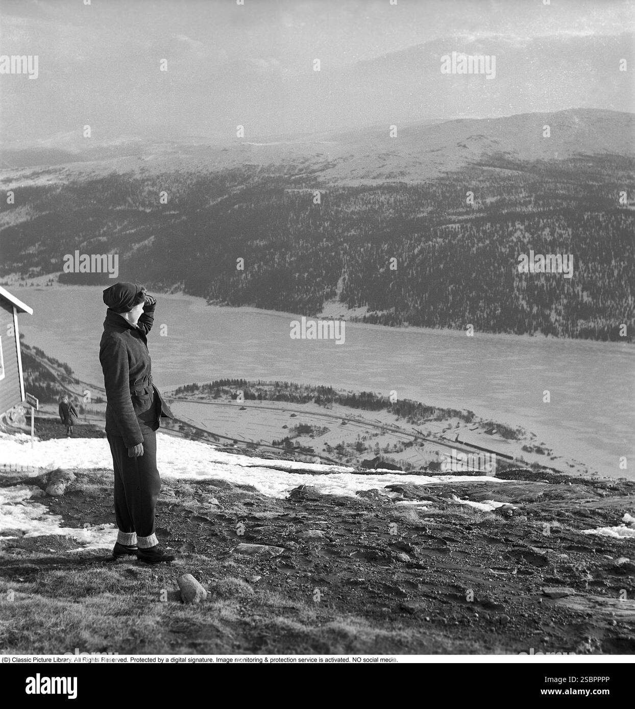 Åre 1952. La station de sports d'hiver populaire à Jämtland Suède où les gens vont skier et socialiser. Åre est connue pour sa longue histoire du ski et les années 1950 étaient une époque où le ski était une attraction sportive et touristique croissante. La photo est prise pendant les jours de l'inauguration de la remontée mécanique de Åre le 5 avril 1952. Une personne est au sommet de la colline avec une vue sur la vallée ci-dessous. Banque D'Images