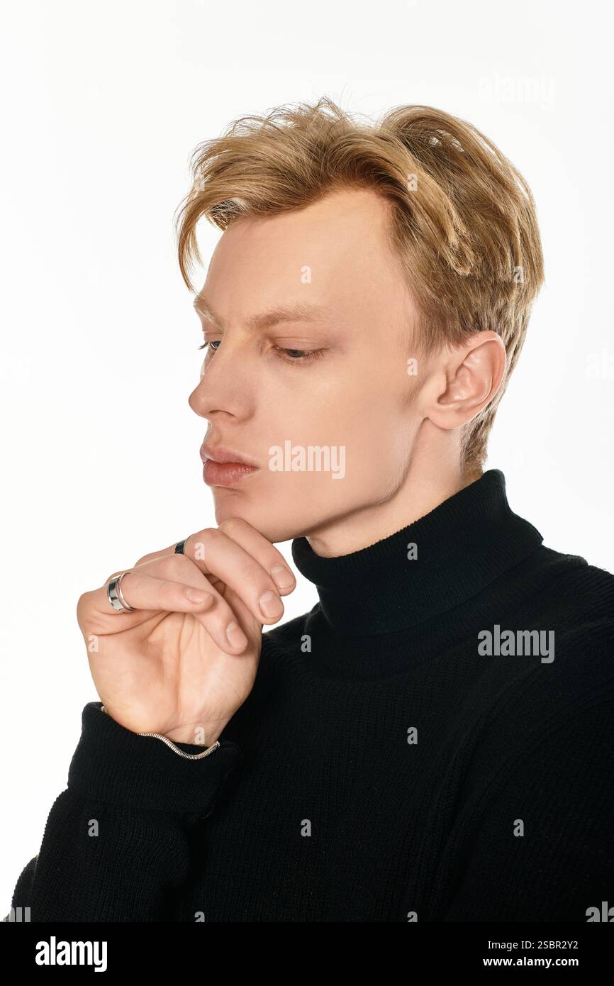 Un jeune homme saisissant contemple profondément, mettant en valeur son élégance dans une pièce élégante et moderne. Banque D'Images