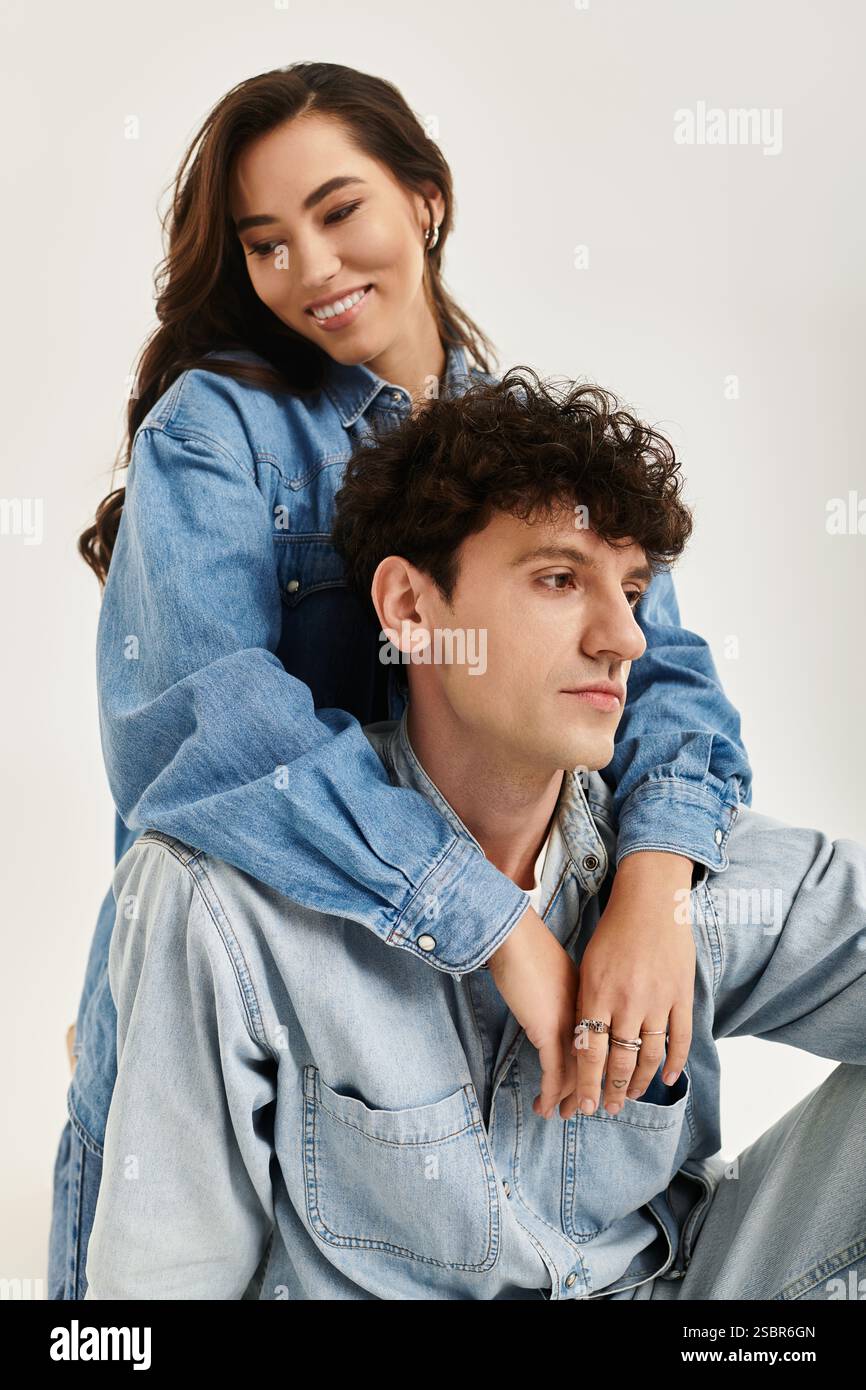 Un jeune couple à la mode pose ensemble dans des tenues en denim à la mode, rayonnant style et confiance. Banque D'Images