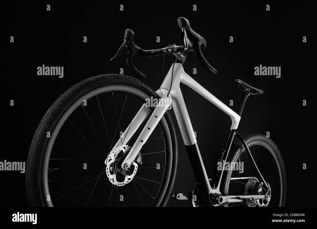 Vélo gravier noir et blanc, prise de vue dynamique depuis le bas de la roue avant sur fond noir. Banque D'Images