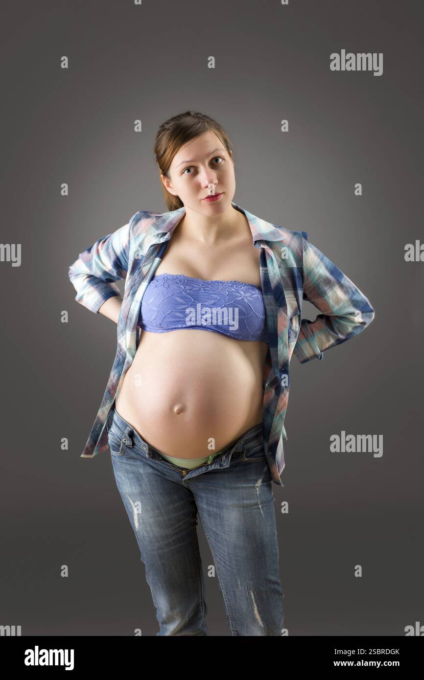 Heureuse jeune femme enceinte sur fond gris Banque D'Images