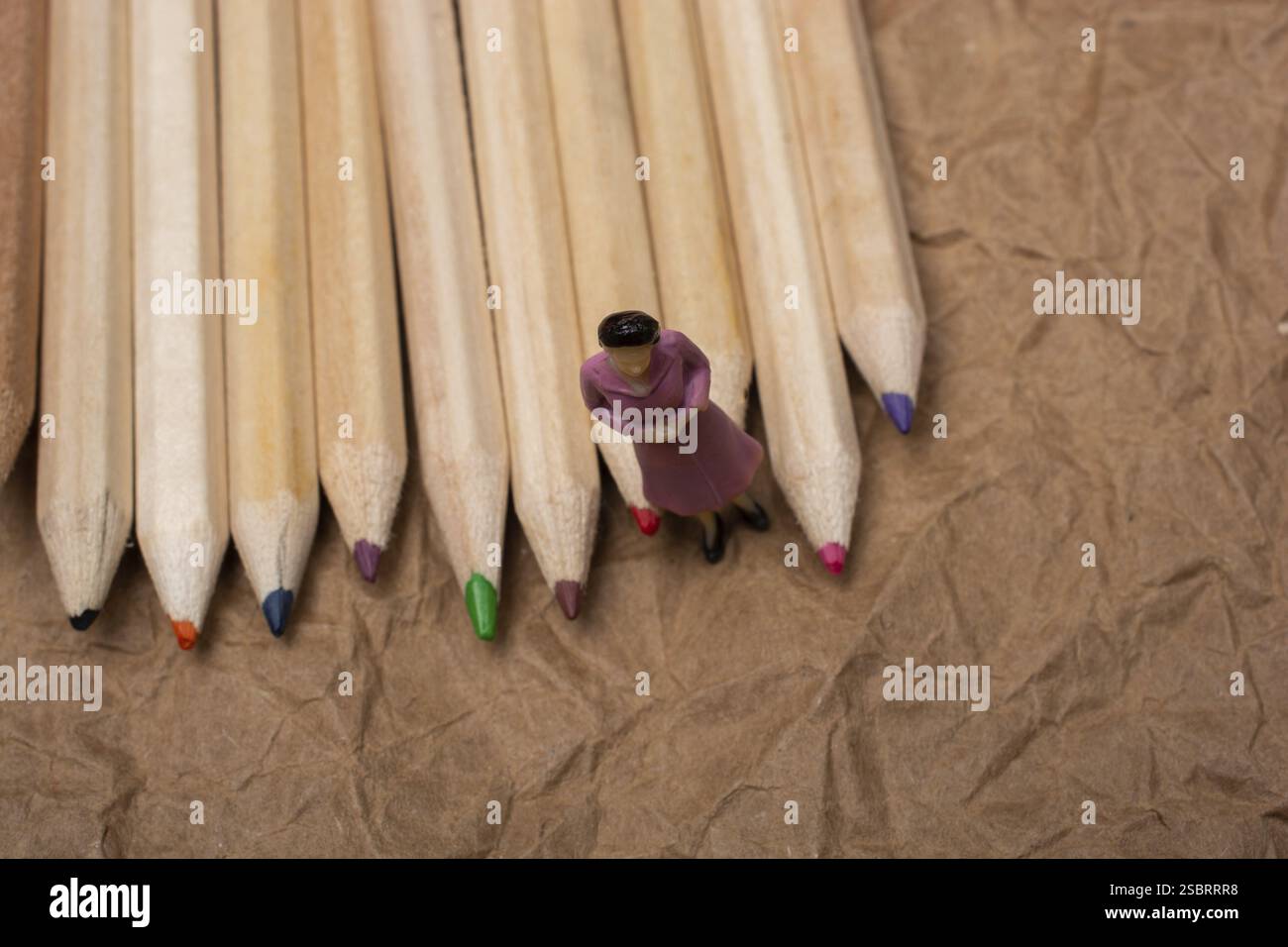 Crayons de couleur sur fond de papier avec une figurine de femme Banque D'Images