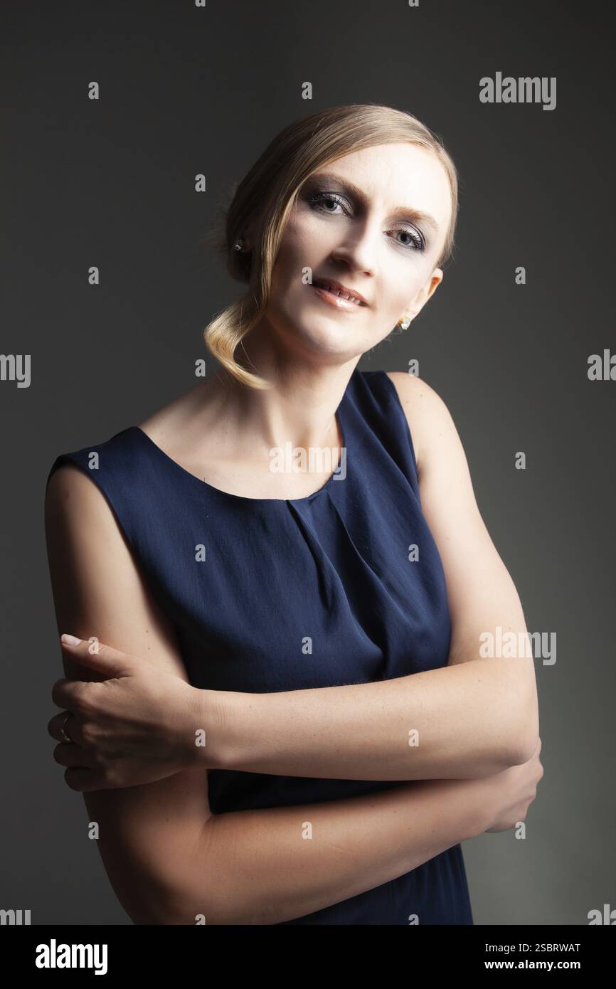 Portrait d'une femme aux cheveux blonds parfaits et maquillage. Sur fond gris Banque D'Images