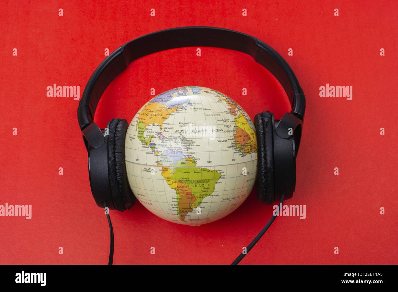 Micro-casque sur globe isolé sur le rouge Banque D'Images